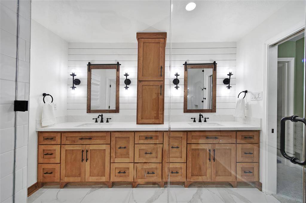 The primary bath features dual sinks and a stylish vanity with shaker flat panel cabinet doors in a full overlay design, complemented by sleek pull-out "style" drawers on both sides for added convenience. Upper cabinet is 12" deep.