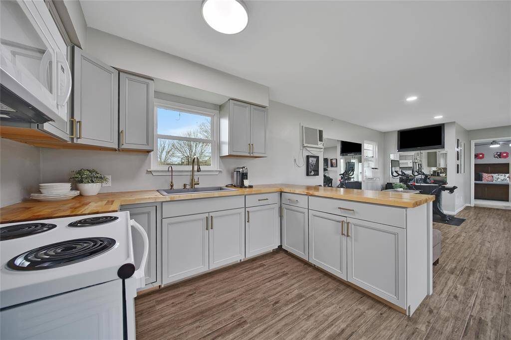 Style meets function in the fully remolded (2022) guest house kitchen featuring wood block counter tops, range, microwave and full sized refrigerator.