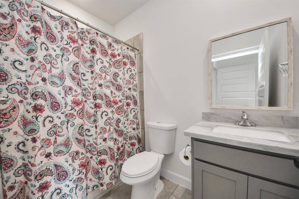The guest bathroom features modern fixtures, a sleek vanity, and a combination tub and shower.
