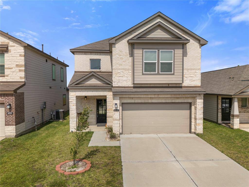 This photo shows a modern two-story house with a clean exterior, a light brick façade, with a double garage. It's situated on a neatly maintained lawn with a small tree, and over time, provides a beautiful addition to the landscape.