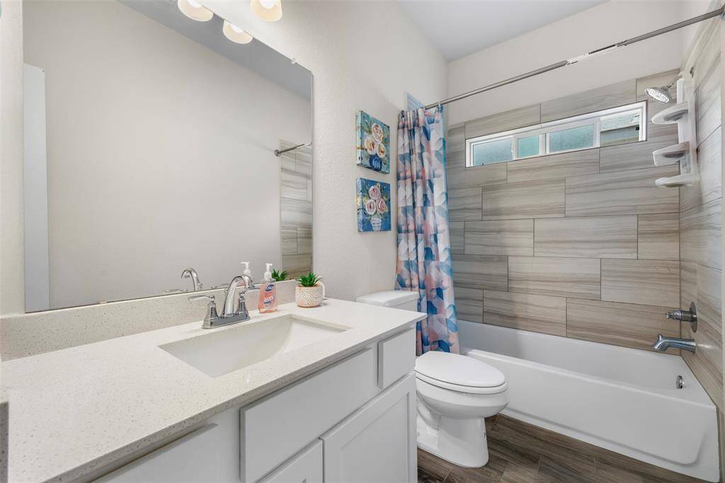 This bathroom features a modern design with a sleek vanity and large mirror. It includes a bathtub with stylish tile surround. The space is bright and inviting, perfect for relaxation.