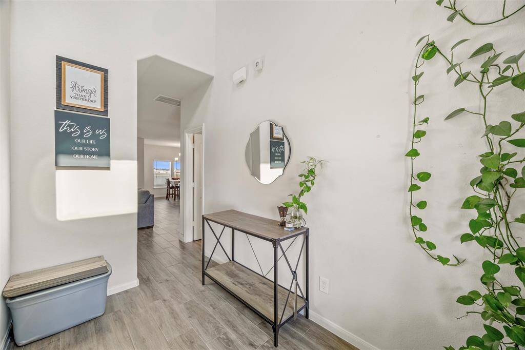 This inviting entryway features light wood flooring that extends into the visible living space, creating a cohesive and welcoming atmosphere in the 2-story entry.