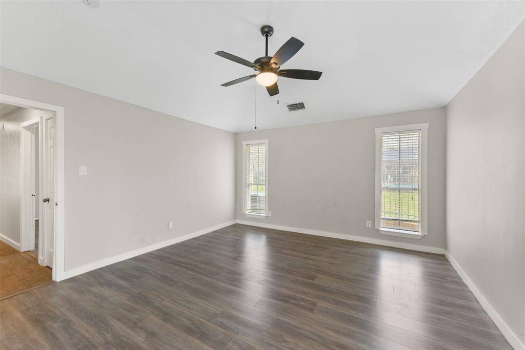 At the far end of the hallway, escape to this peaceful owners retreat complete with a modern lighted ceiling fan, numerous cased windows dressed with 2-inch blinds, wood-look tile floors, neutral paint, and a pocket door to the en suite bathroom.
