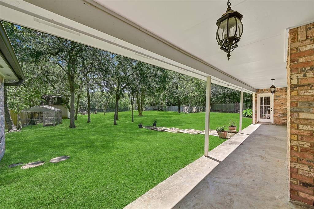 A half-panel glass door leads from the flex-use bonus room onto the lengthy covered back patio overlooking the huge 1.17-acre yard that includes a storage shed, a separate fenced pet area, and Spanish moss-draped trees sloping down to the creek bank.