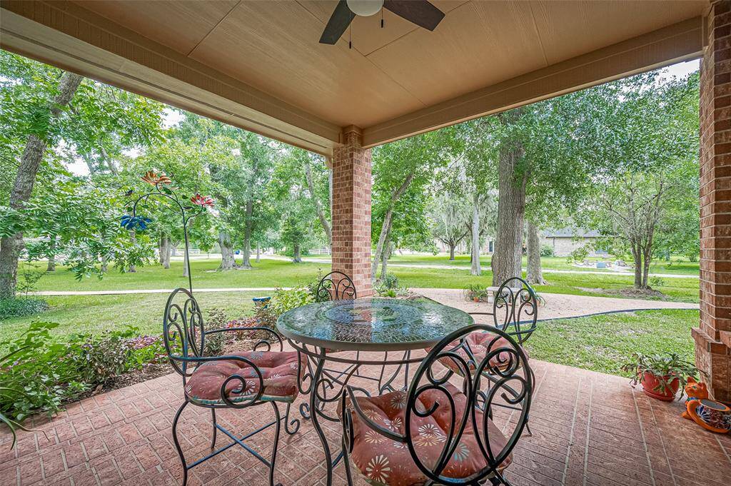 Covered porch overlooking the front yard full of large trees.