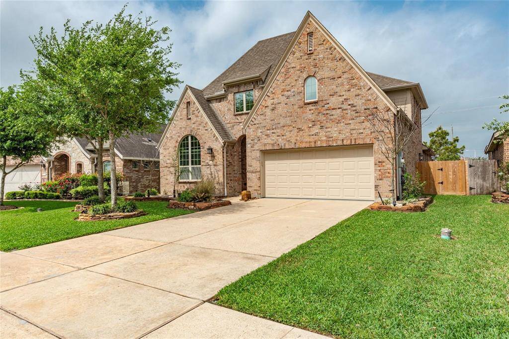 Enviable curb appeal featuring professional landscaping with stacked-stone flowerbeds, green shrubs & superb drainage system.