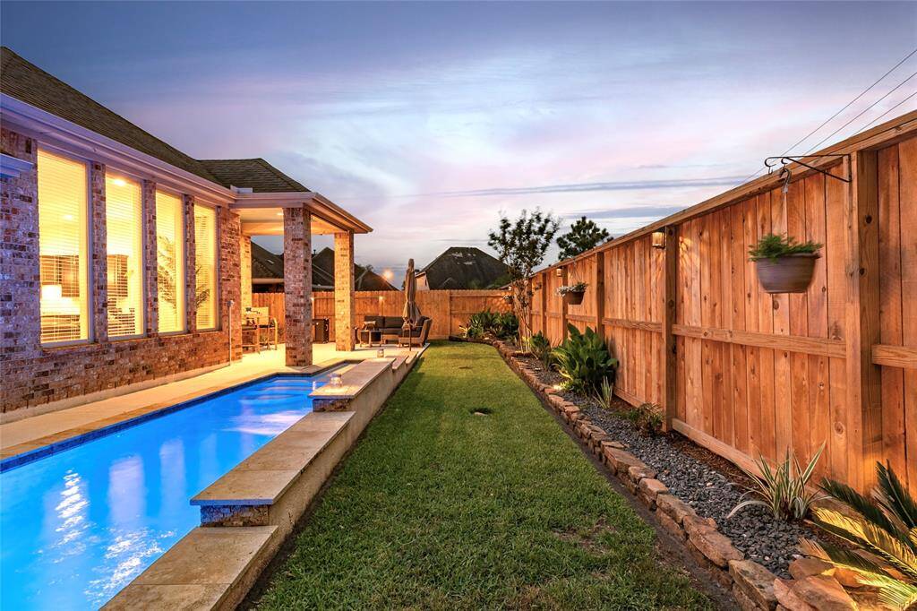 Take an early morning swim, or evening plunge! This inviting backyard features a sleek lap pool alongside the brick home and patio, perfect for entertaining. The space is bordered by a privacy fence with professional landscaping & solar lighting, offering a serene and private outdoor retreat.