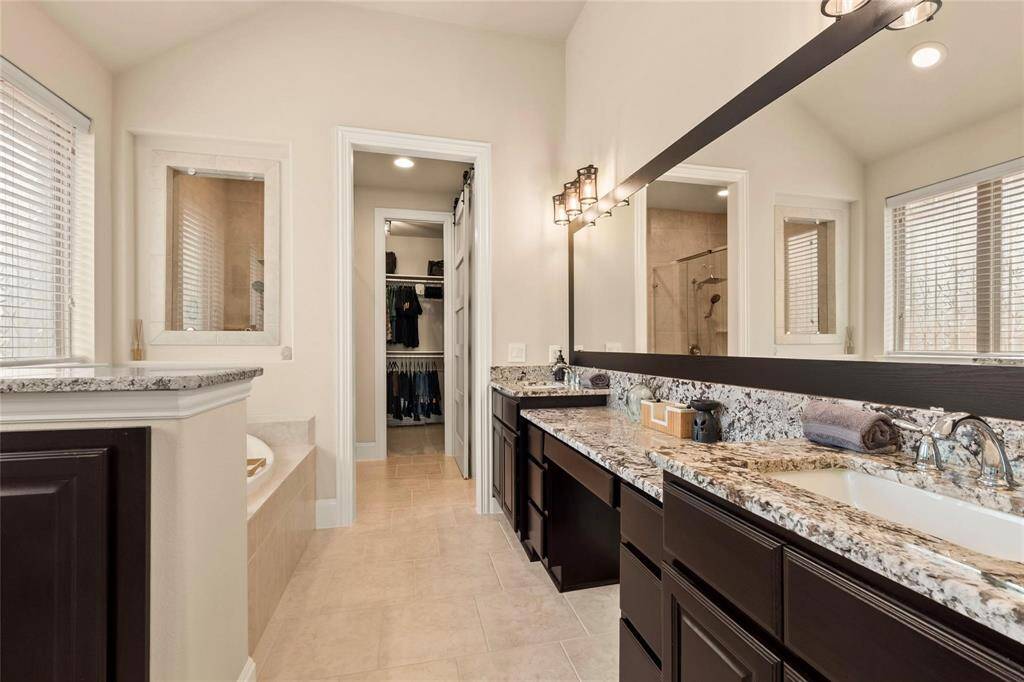 8-foot high interior doors throughout. Glass-enclosed shower and a walk-in closet. The space is well-lit, featuring neutral tones and a clean, organized appearance.