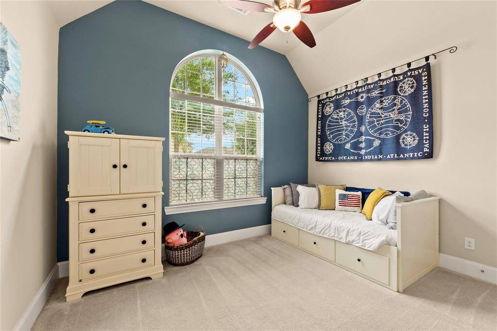 This bedroom features a vaulted ceiling with a fan, and a large arched window for natural light.