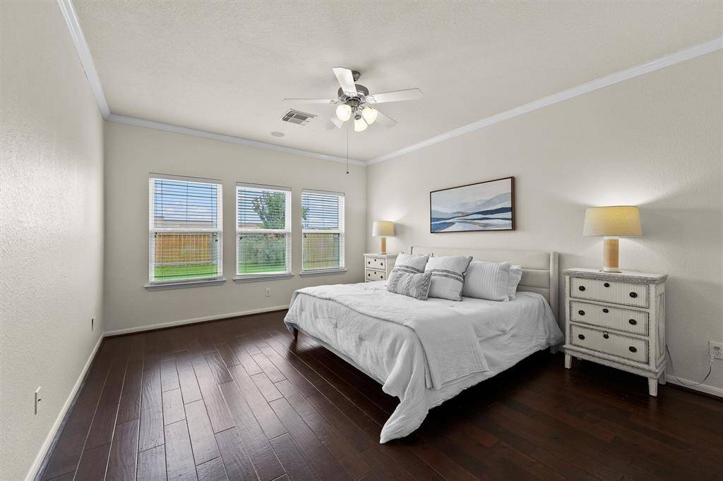 Spacious primary bedroom with engineered hardwood floors and ceiling fan.