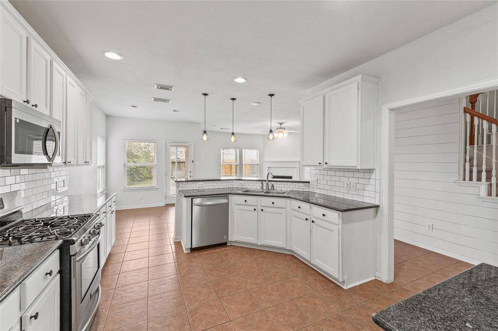 The kitchen features stainless steel appliances and pendant lights over the breakfast bar.