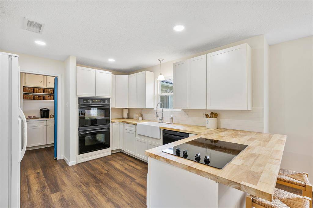 This modern kitchen includes all appliances and features new butcher block countertops (2025) and a charming farmhouse porcelain sink with a scenic window view.