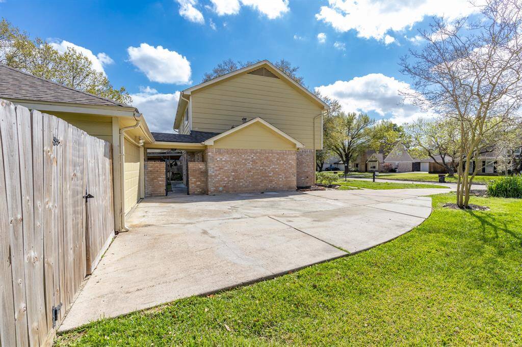 Expansive driveway with an elegant iron and brick gate leading to a spacious backyard.