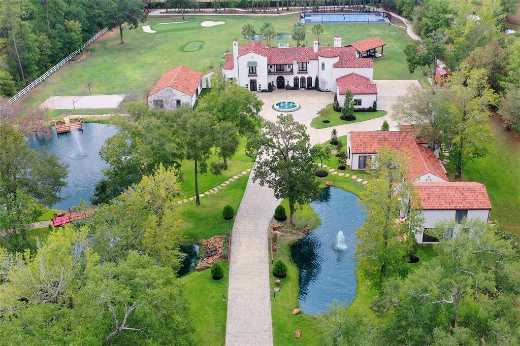 Stunning aerial view of this colonial-style estate, complete with two lakes, sports courts, and a thrilling go-kart track!