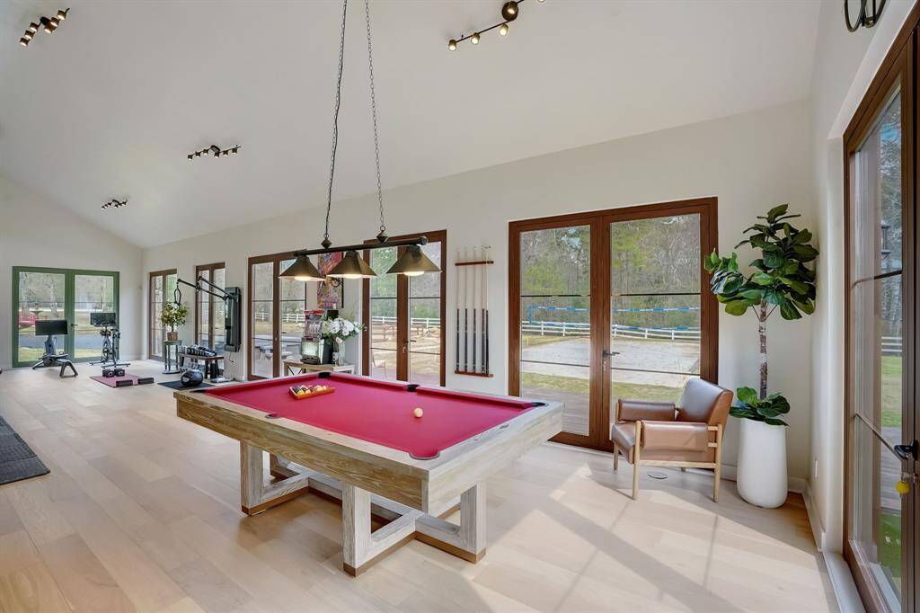 Bright and spacious room with a home gym and pool table, flooded with natural light for a vibrant atmosphere."