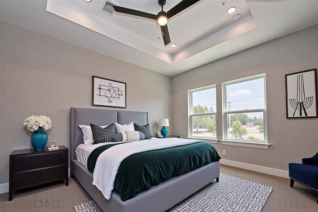 Retreat to this elegantly staged primary suite featuring a tray ceiling with recessed lighting, expansive windows that flood the room with natural light, and a bold yet serene design that balances comfort and style. A true sanctuary to unwind.