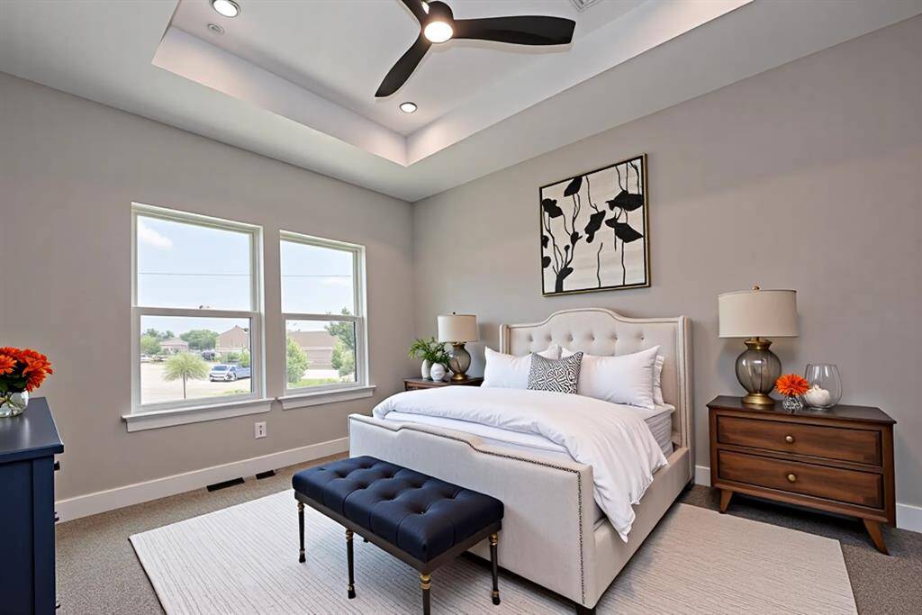 This sunlit secondary bedroom offers a peaceful escape with its elegant tray ceiling, soft neutral palette, and stylish design. Ample natural light and thoughtful staging make it perfect for guests, a home office, or a cozy retreat.