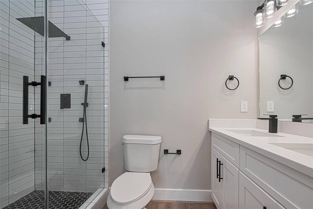 Spa-Inspired SerenityStep into this glass-enclosed shower featuring sleek subway tile, hexagon tile flooring, and dual showerheads—including a rainfall fixture for a true spa experience. The double vanity with matte black accents and custom lighting completes this modern retreat.