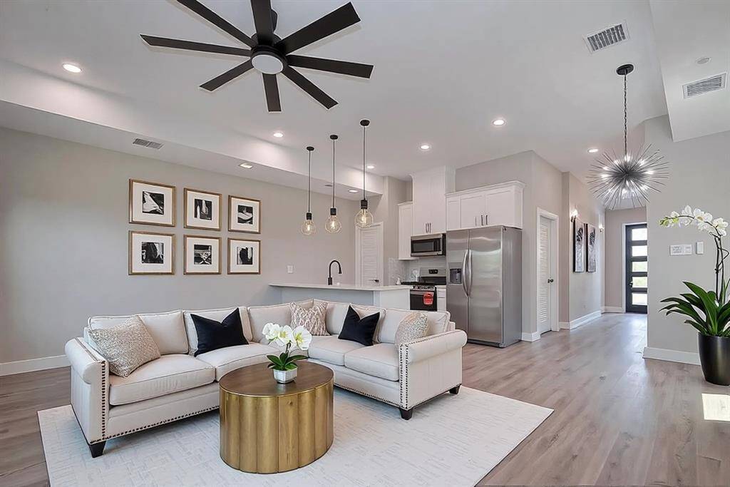 Open-Concept Layout Designed to ImpressThe heart of the home shines with high ceilings, oversized modern ceiling fans, and a seamless flow between the kitchen, dining, and living areas. The stylish kitchen boasts sleek white cabinetry, stainless steel appliances, quartz countertops, a striking black faucet, and designer pendant lights. A dramatic starburst chandelier anchors the dining space, adding flair to every meal and gathering.