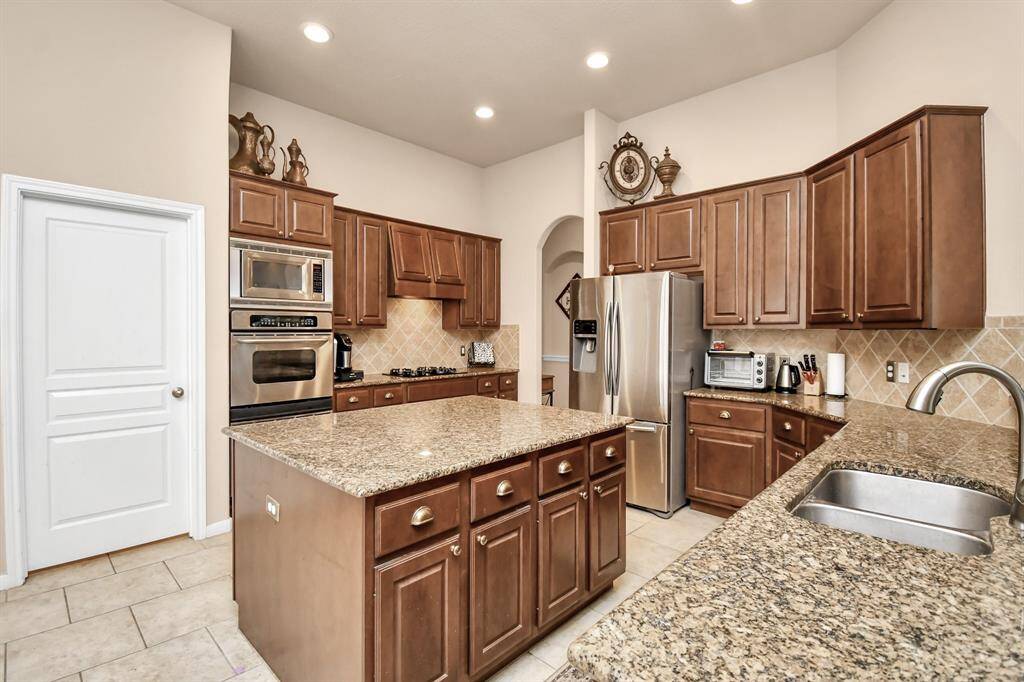 Stainless steel appliances, including double ovens and a gas cooktop, add a touch of luxury to the kitchen, enhancing both its functionality and aesthetics.