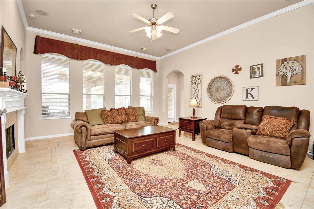 The spacious neutral palette carries into the den, with a wall of windows flooding the space with natural light and overlooking the expansive back covered patio and yard.