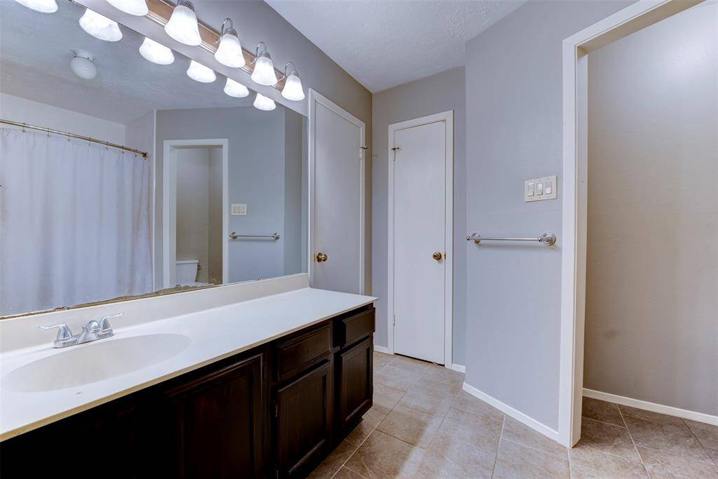 A long white quartz countertop provides ample space around the single sink for daily essentials. A tucked-away water closet adds extra convenience, completing this well-appointed and functional bathroom.
