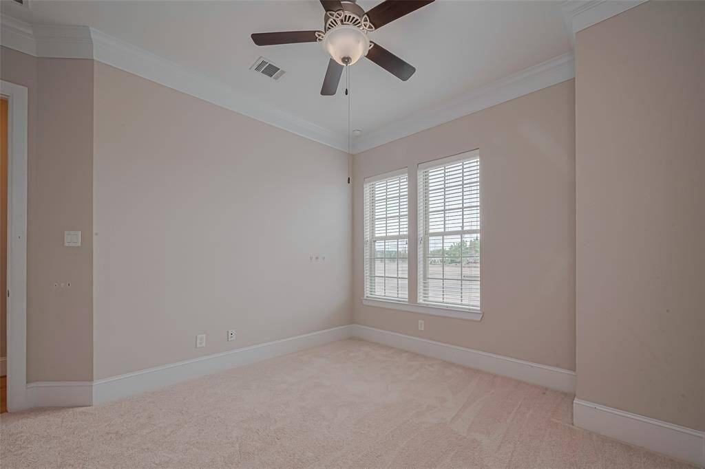 Second-floor secondary bedroom featuring plush carpet, crown molding, ceiling fan, and neutral tones. This versatile space is ideal for a guest room, home office, or cozy retreat.