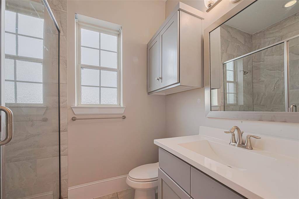 Located on the second floor, this full bathroom features a sleek walk-in shower with modern tile surround, a spacious vanity with quartz countertop, brushed nickel fixtures, and upper cabinet storage. Perfectly positioned to serve both the second-floor bedroom and guests alike.