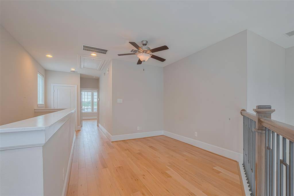 Third-floor flex space with wood flooring, ceiling fan, and a modern iron railing overlooking the stairs. Ideal for a home office, reading nook, or play area—this versatile landing offers additional living space with multiple potential uses.