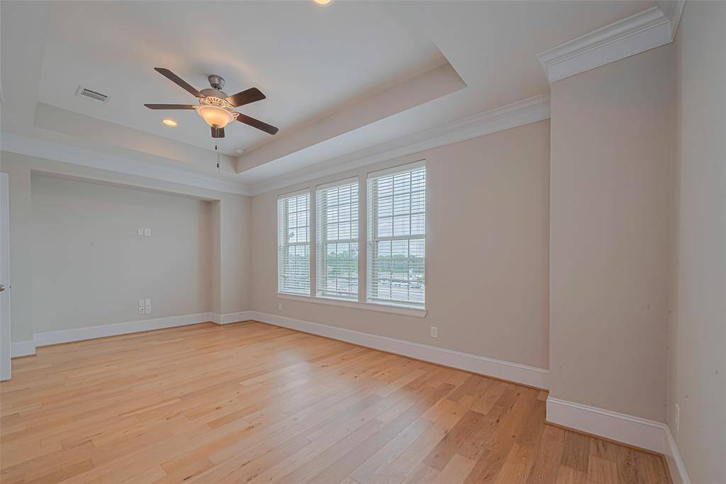 The 3rd-floor Primary Bedroom is a private and spacious retreat with no other rooms on this level. It features beautiful hardwood flooring, a high tray ceiling with crown molding, and a wall of windows that fills the room with natural light. The open layout provides ample space for a king-sized bed plus a sitting area or workspace.