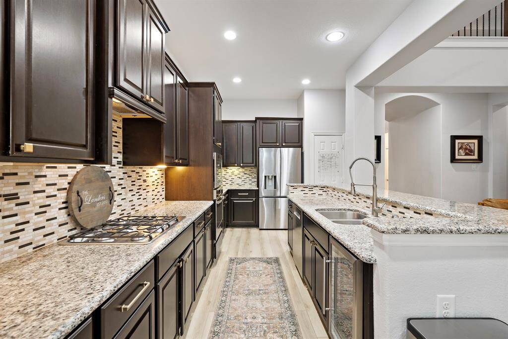 The kitchen offers a seamless blend of modern functionality and elegant design, featuring granite countertops, custom dark wood cabinetry, a premium gas cooktop, and an inviting open-concept layout perfect for both everyday living and entertaining.