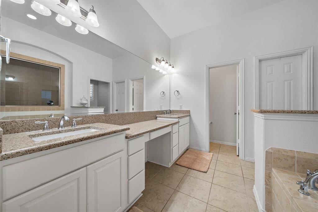 The primary bathroom features a dual vanity with granite countertops and ample storage, providing a luxurious and functional space.