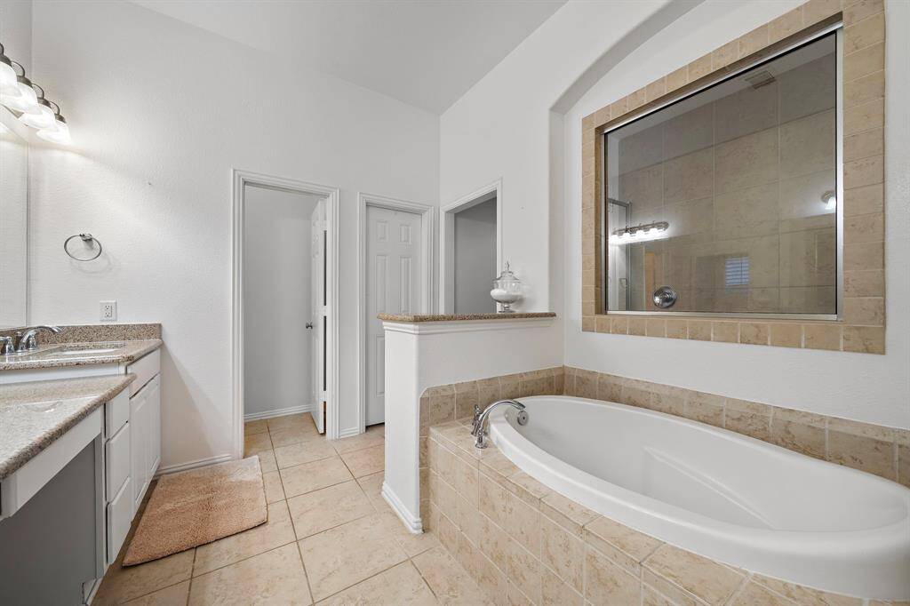 A spacious soaking tub and a separate glass-enclosed shower are highlights of the en suite bathroom, offering spa-like comfort.