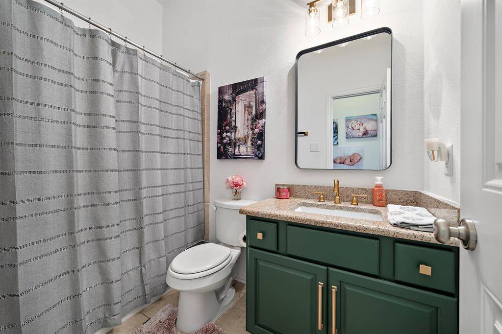 The en-suite bathroom features elegant granite countertops and a sleek modern mirror. This bathroom complements the adjoining bedroom, making it an ideal private retreat for guests or family members.