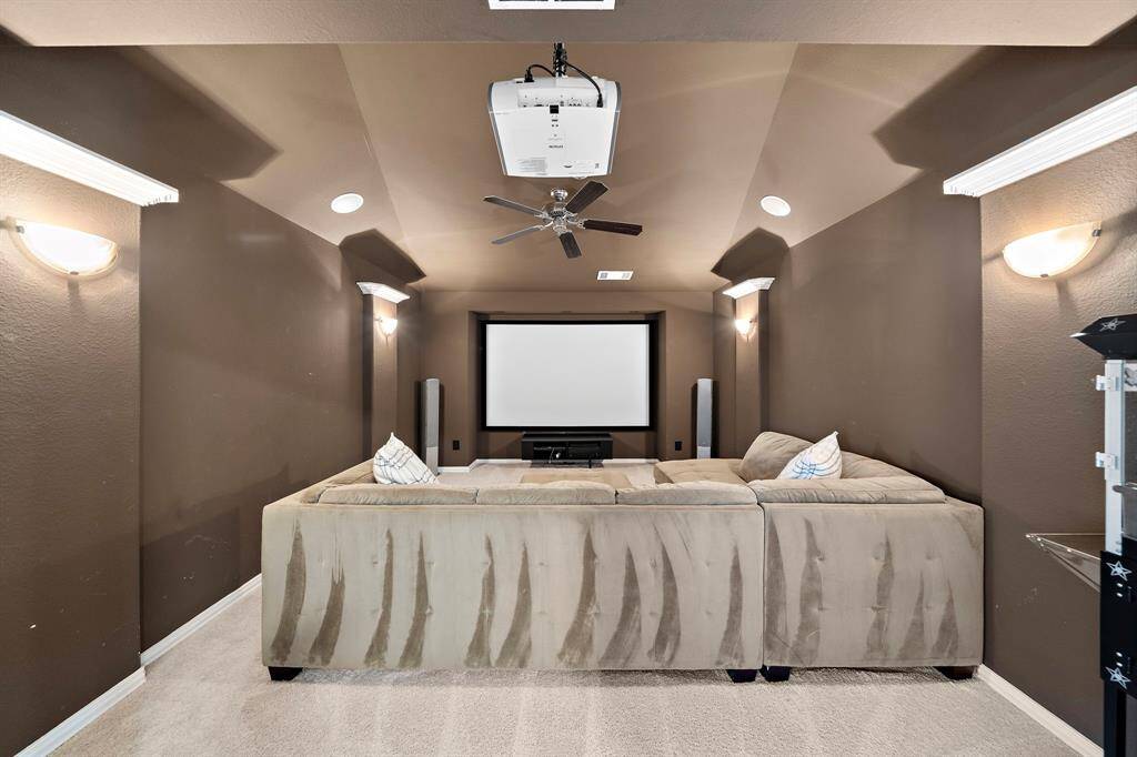 The dedicated media room boasts a theater-like atmosphere with dark walls and soft carpeting, perfect for enjoying movie nights in comfort.