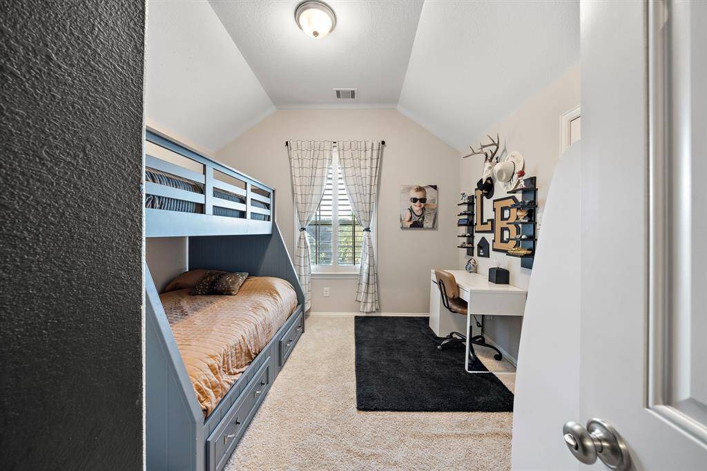 Secondary bedroom with vaulted ceilings and soft carpet for comfort.