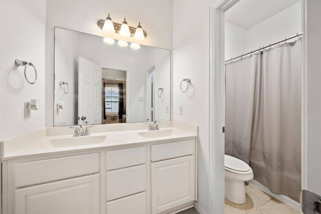 Stylish and functional bathroom featuring a large vanity with dual sinks and easy access to all secondary bedrooms
