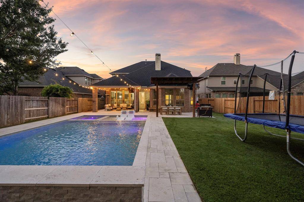 Custom-designed for entertaining, this backyard features a pergola-covered dining space and a cozy fire pit area.