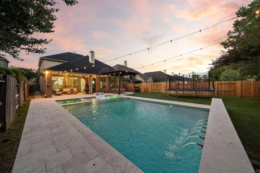 The luxurious pool area is the heart of the backyard, complete with elegant water features and ample deck space for sunbathing.