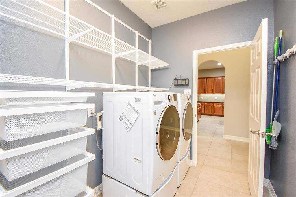 Large utility room with front load washer and dryer. Custom build in baskets and shelving with door leading to the oversized garage.