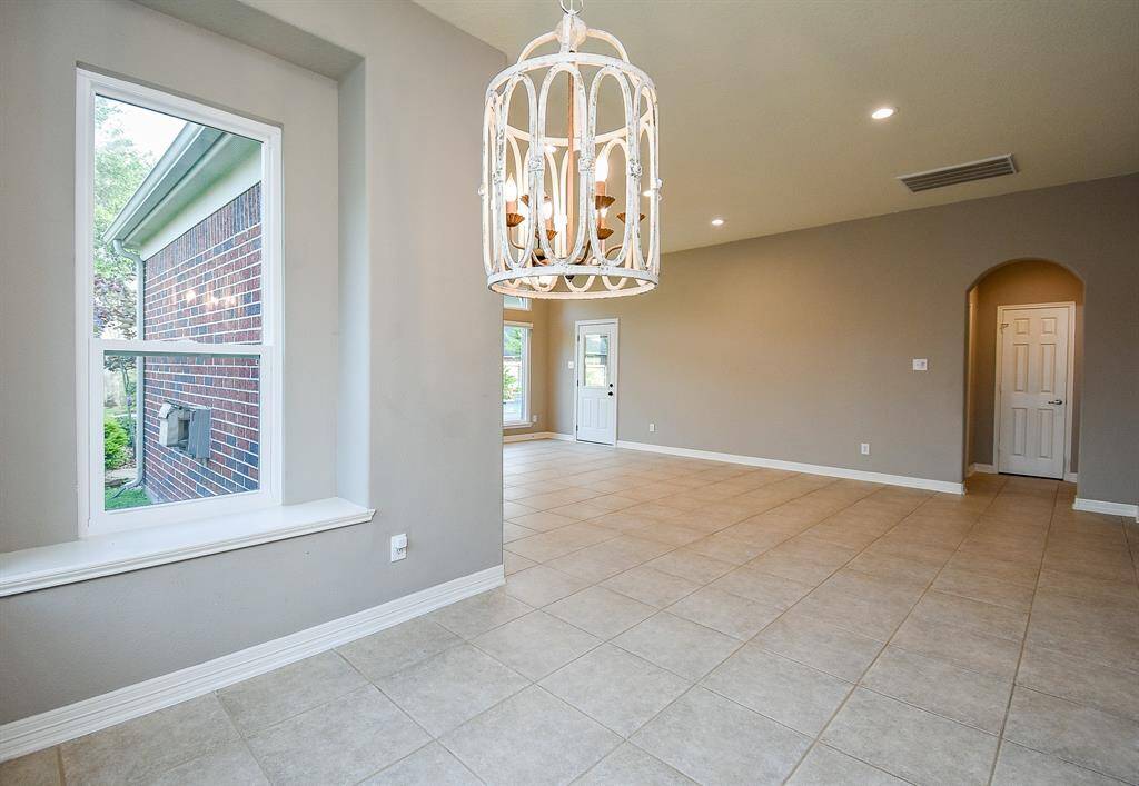 Breakfast room with custom chandelier, windows looking out over the lush backyard bring in lots of natural light. This space is open to the family room and kitchen.