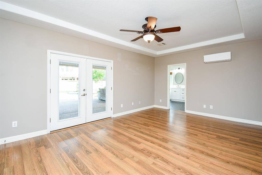 Primary bedroom with double doors leading to oversized covered patio, pool and huge backyard. A Mini split has been added for extra cooling when desired.