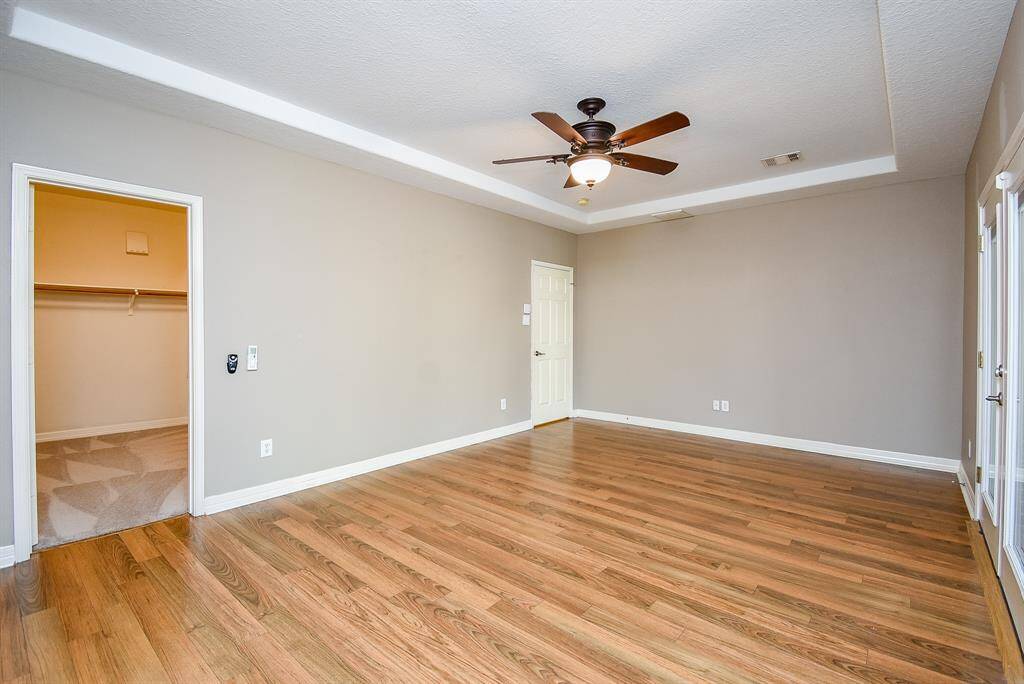 Primary bedroom with ceiling fan and wood flooring.