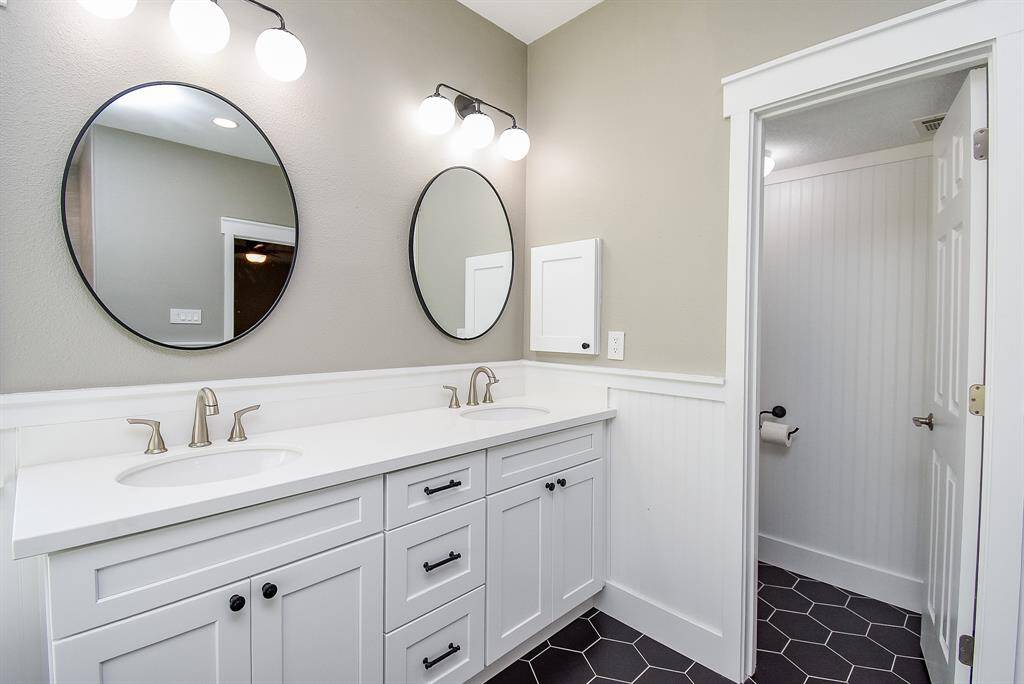 New updated primary bathroom with new cabinet, paint, flooring, vanity lights, mirrors, sinks, faucets and hardware.
