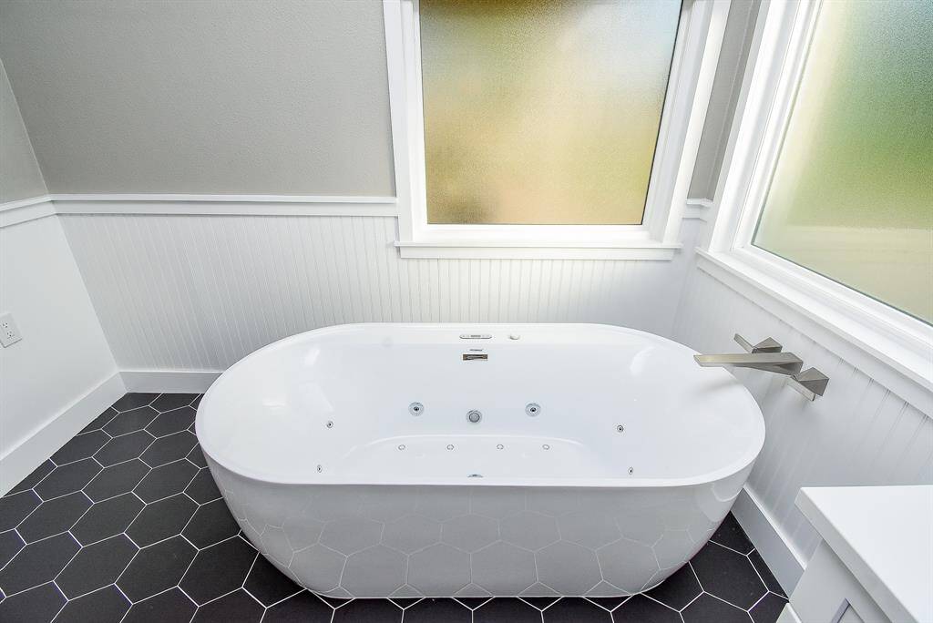 New Air Jacuzzi standalone tub surrounded by rain glass windows and remove WiFi shades for privacy. Beautiful contract with hexagon tile and accented beadboard.