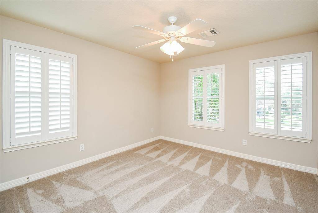Another secondary bedroom upstairs with neutral colored carpet and paint.  Walls of windows bring in lots of natural light.