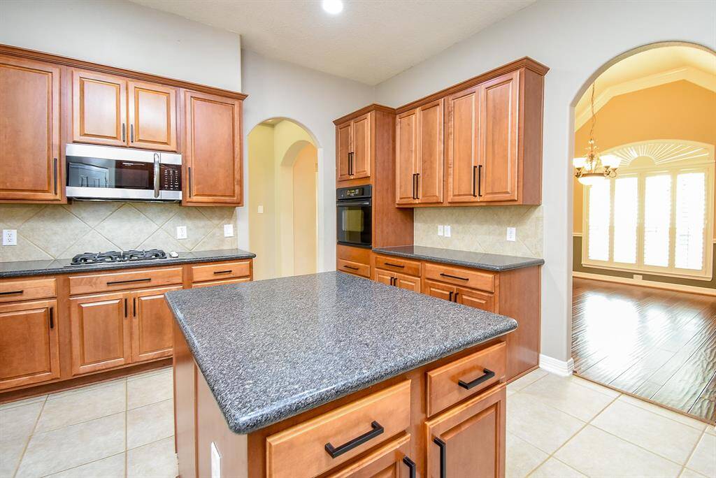 Arched openings from dining room and entry lead to kitchen with island, which is great for prepping, gas cook top, build in microwave and oven.