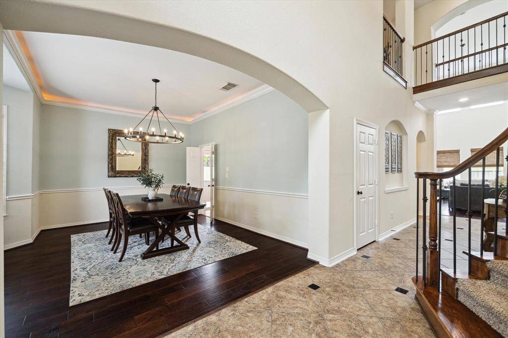 This elegant formal dining room, positioned directly across from the study, exudes sophistication with its classic design. The space features plantation shutters on the windows, allowing for adjustable natural light, and upgraded lighting that enhances the room's ambiance.