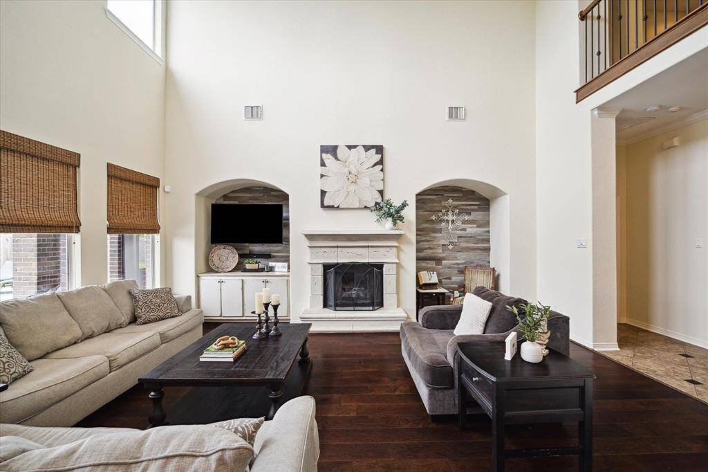 The space is accented by a stone fireplace with rustic wood-paneled niches, creating a cozy focal point, and an open layout that seamlessly connects to adjacent areas.
