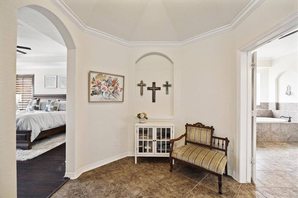 Transitional space connecting the primary bedroom to the ensuite bathroom, featuring a cozy nook with decorative architectural details such as curved archways and crown molding.